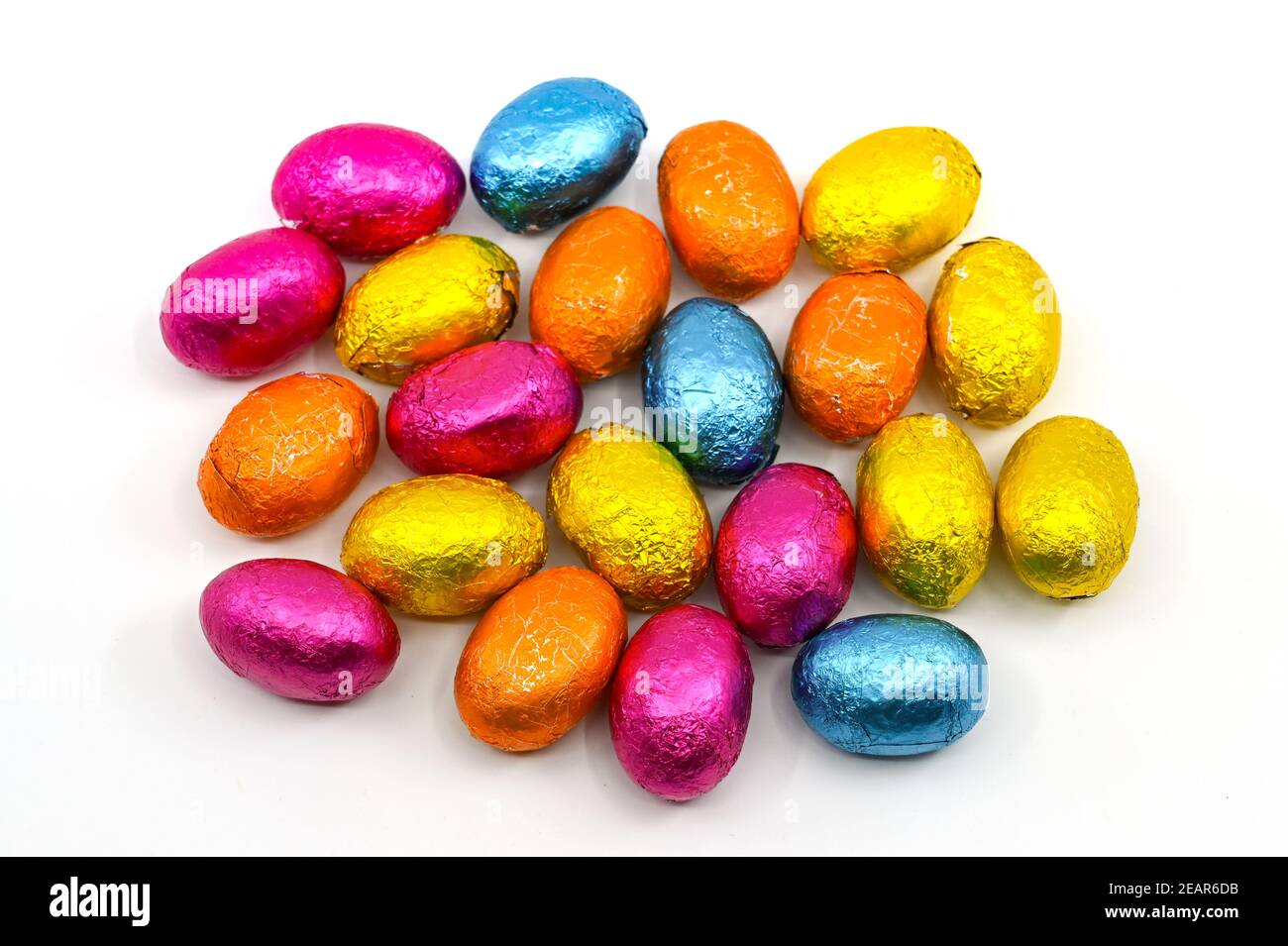 Kleine Schokoladen-Ostereier in farbigen Folienverpackungen auf einem schlichten Hintergrund. Keine Personen. Stockfoto