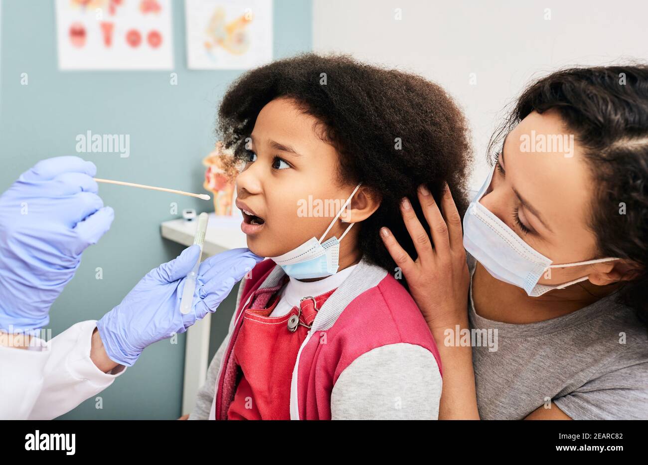 Afroamerikanisches kleines Mädchen mit Elternteil während PCR-Test auf COVID-19 in einem medizinischen Labor. Arzt nimmt einen oralen Tupfer für Coronavirus-Probe Stockfoto