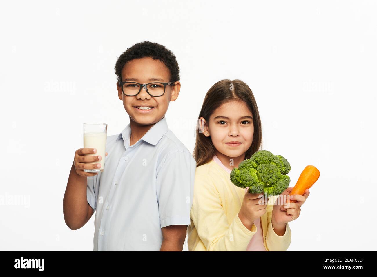 Latino-Amerikanisches Mädchen und afroamerikanischer Junge mit gesundem Essen und Milch. Gesunde Ernährung von Kindern Stockfoto