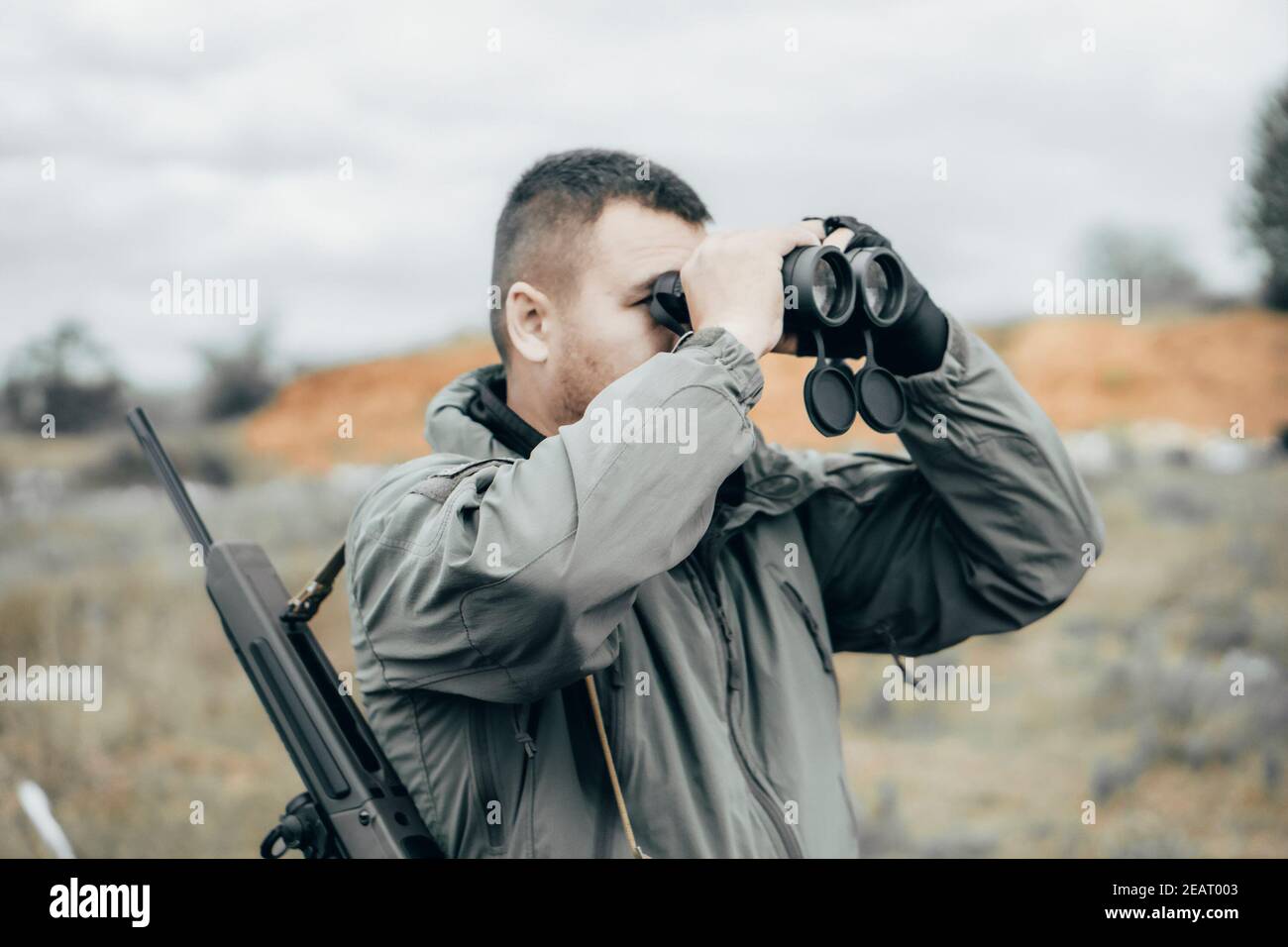 Mann mit einem Gewehr, der durch ein Fernglas schaut. Private militärische  Auftragnehmer oder Jäger Stockfotografie - Alamy