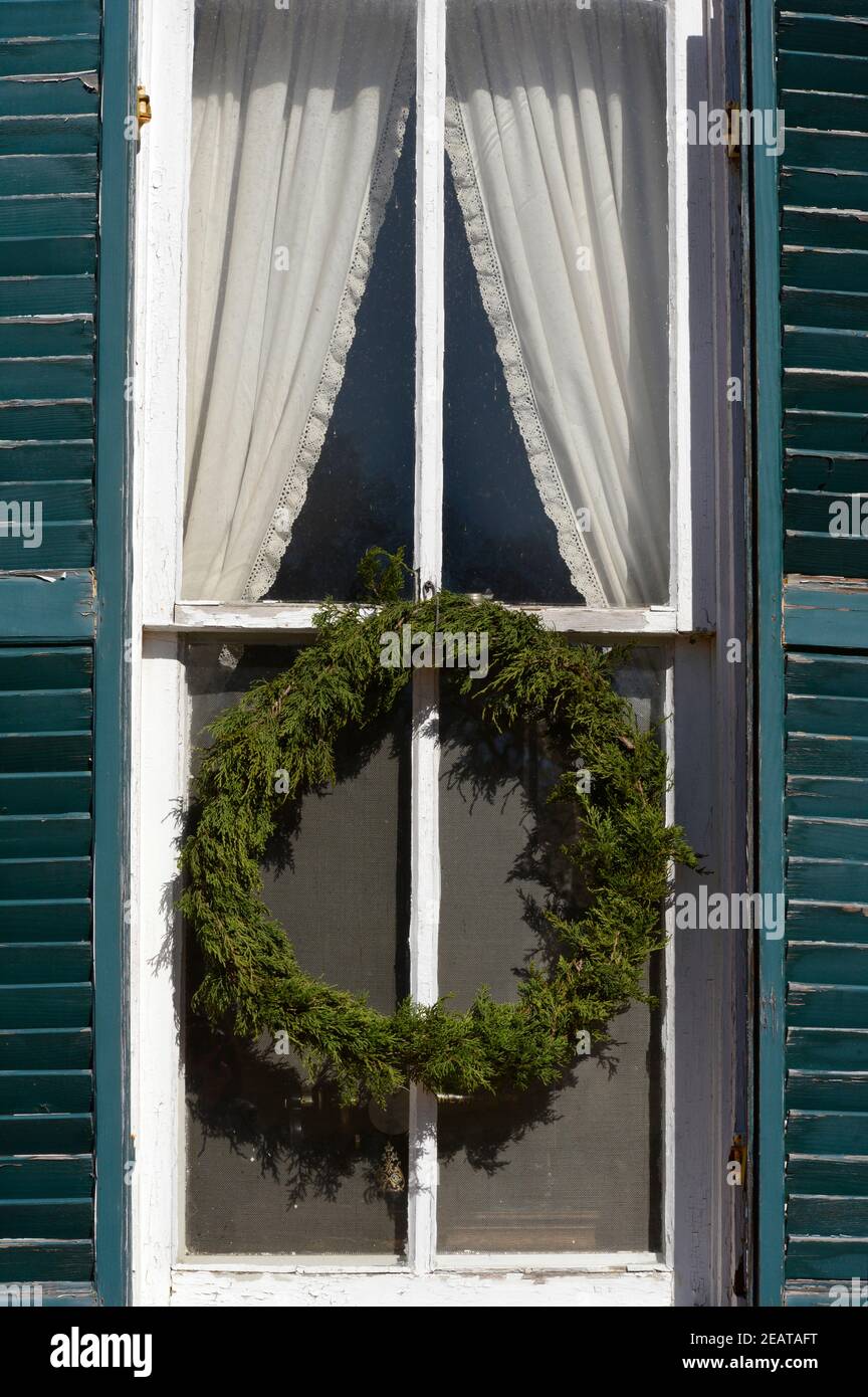 Ein altmodischer handgefertigter Weihnachtskranz hängt an einem historischen Haus auf der Sauer Beckmann Living History Farm in Stonewall, Texas. Stockfoto