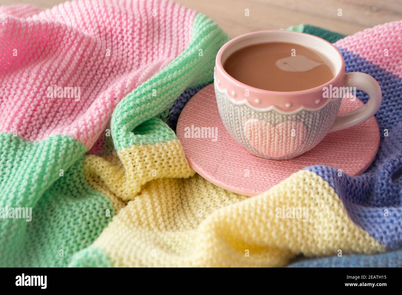 Gestrickte Tasse Kaffee oder Cappuccino auf bunt gestricktem Karo. Good Morning Konzept. Frühstückszeit. Stockfoto