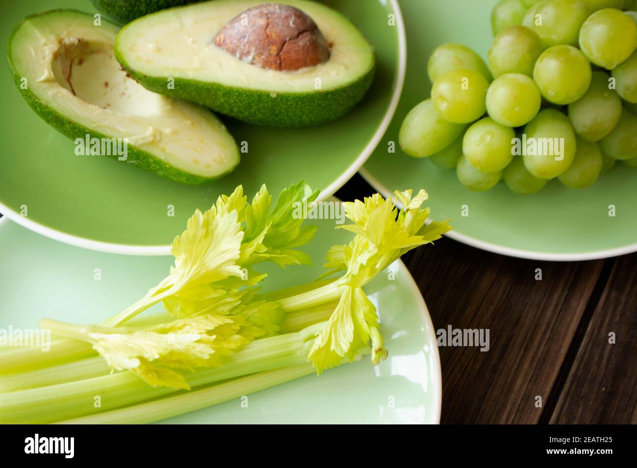 Verschiedene frische grüne Früchte und Gemüse auf grünen Tellern. Das Konzept der gesunden Ernährung. Stockfoto