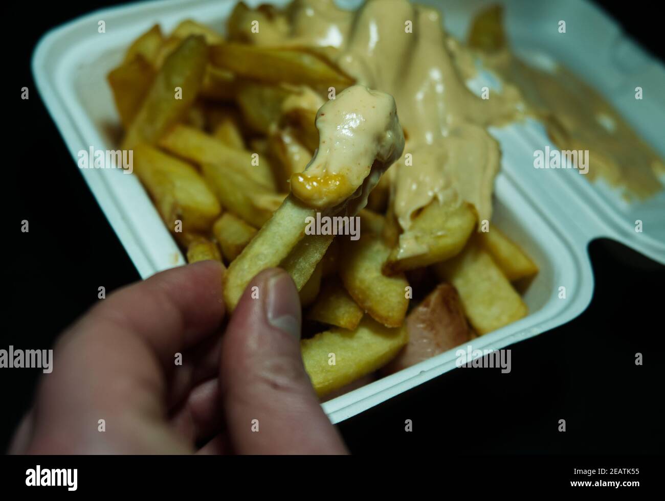 currywurst mit Pommes in eine Tasse auf schwarzem Hintergrund. Traditionelles deutsches Essen mit Dip zu Corona Zeiten, negativer Raum zu gehen Stockfoto