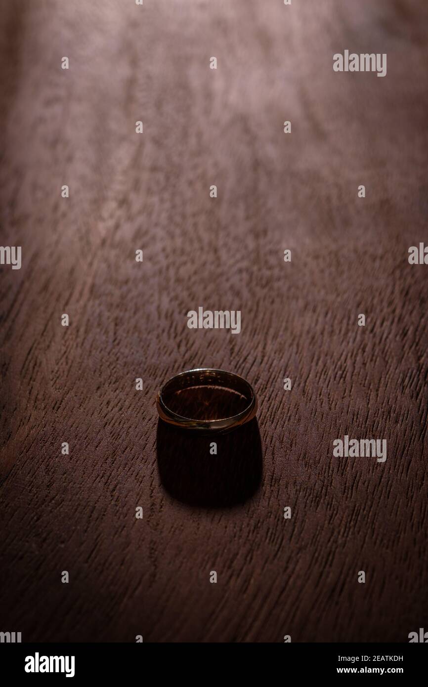 Goldener Ring auf Holzbrett im Hintergrund beleuchtet Stockfoto