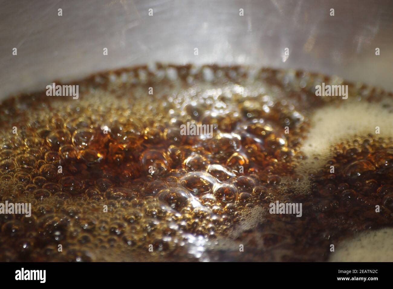 Nahaufnahme Makrofotografie mit selektivem Fokus auf kochendes braunes Wasser Stockfoto