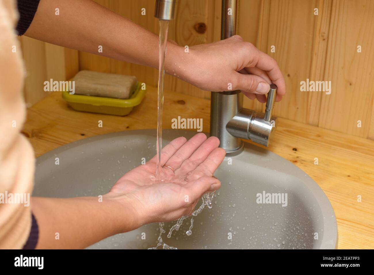 Leitungswasser gießt in die Hand des Mädchens Stockfoto