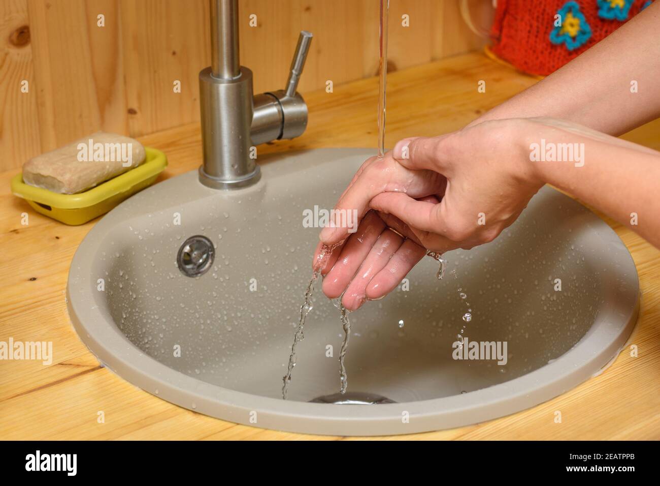 Die Hände des Mädchens werden mit kaltem Leitungswasser gewaschen Ort des Brands auf ihrem Arm Stockfoto