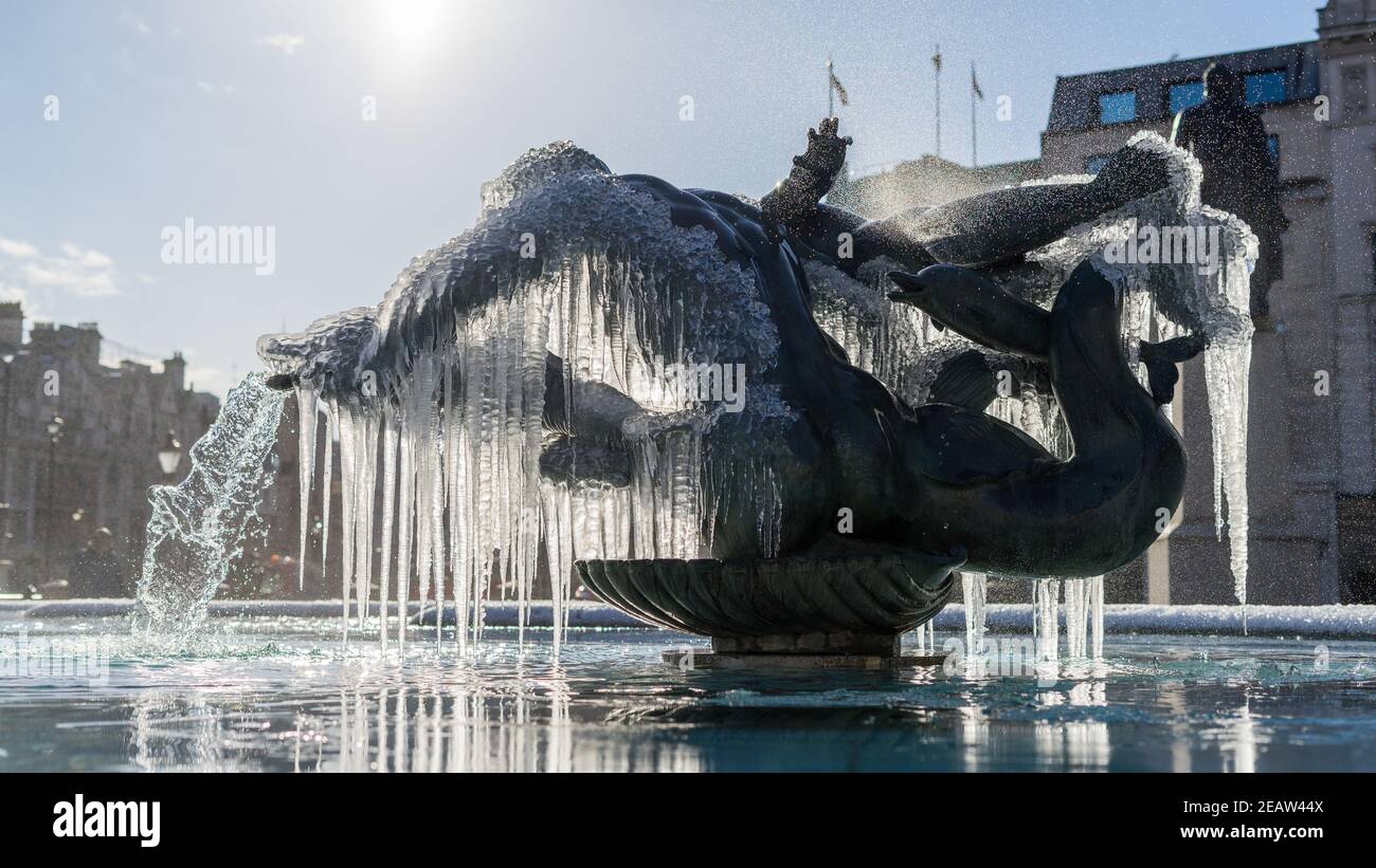 Gefrorene Brunnen Statuen von Trafalgar Square in London. Eiszapfen, die mystisch an einem bronzenen Brunnen hängen Stockfoto