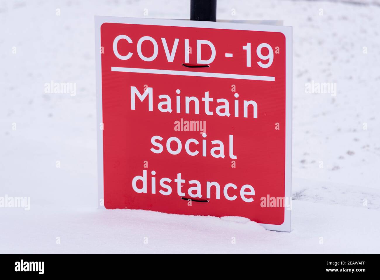 COVID 19, halten soziale Abstand Warnschild in Southend on Sea, Essex, Großbritannien, mit Schnee von Storm Darcy. Auf dem Boden Stockfoto