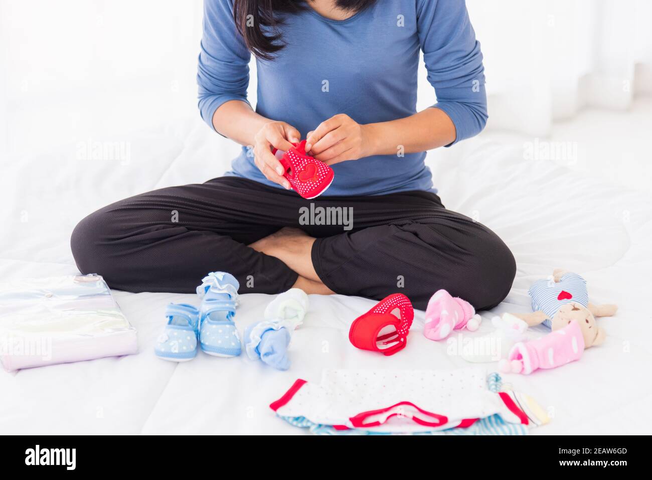 Mutter bereitet Babykleidung vor, die sich auf dem Bett ausruhen und entspannen Stockfoto