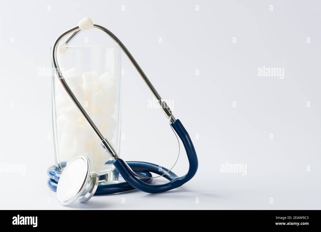 Glas voll von weißem Zucker Würfel süße Lebensmittel Zutat und Arzt Stethoskop Stockfoto