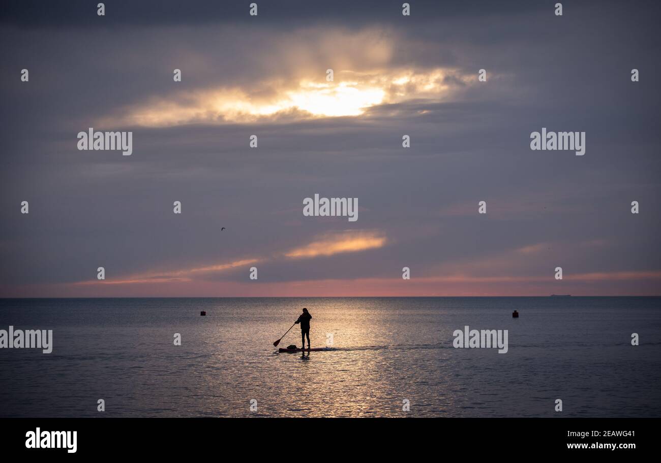 Ein Paddlebarder paddelt bei Sonnenuntergang in der Nähe des West Pier in Brighton, Großbritannien, 6. Februar 2021 Stockfoto