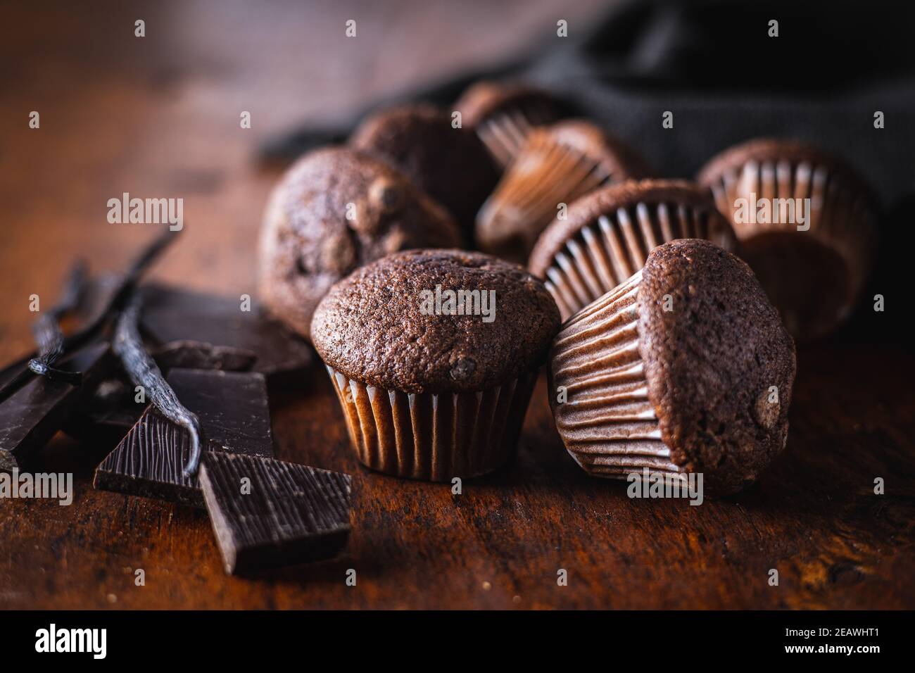 Schokoladen-Muffins. Süße dunkle Cupcakes mit Schokolade und Vanilleschoten auf Holztisch. Stockfoto