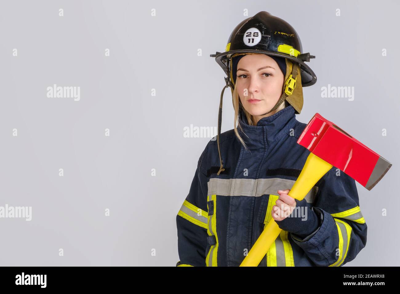 Junge Frau in Uniform der Feuerwehrmann mit Axt Stockfoto