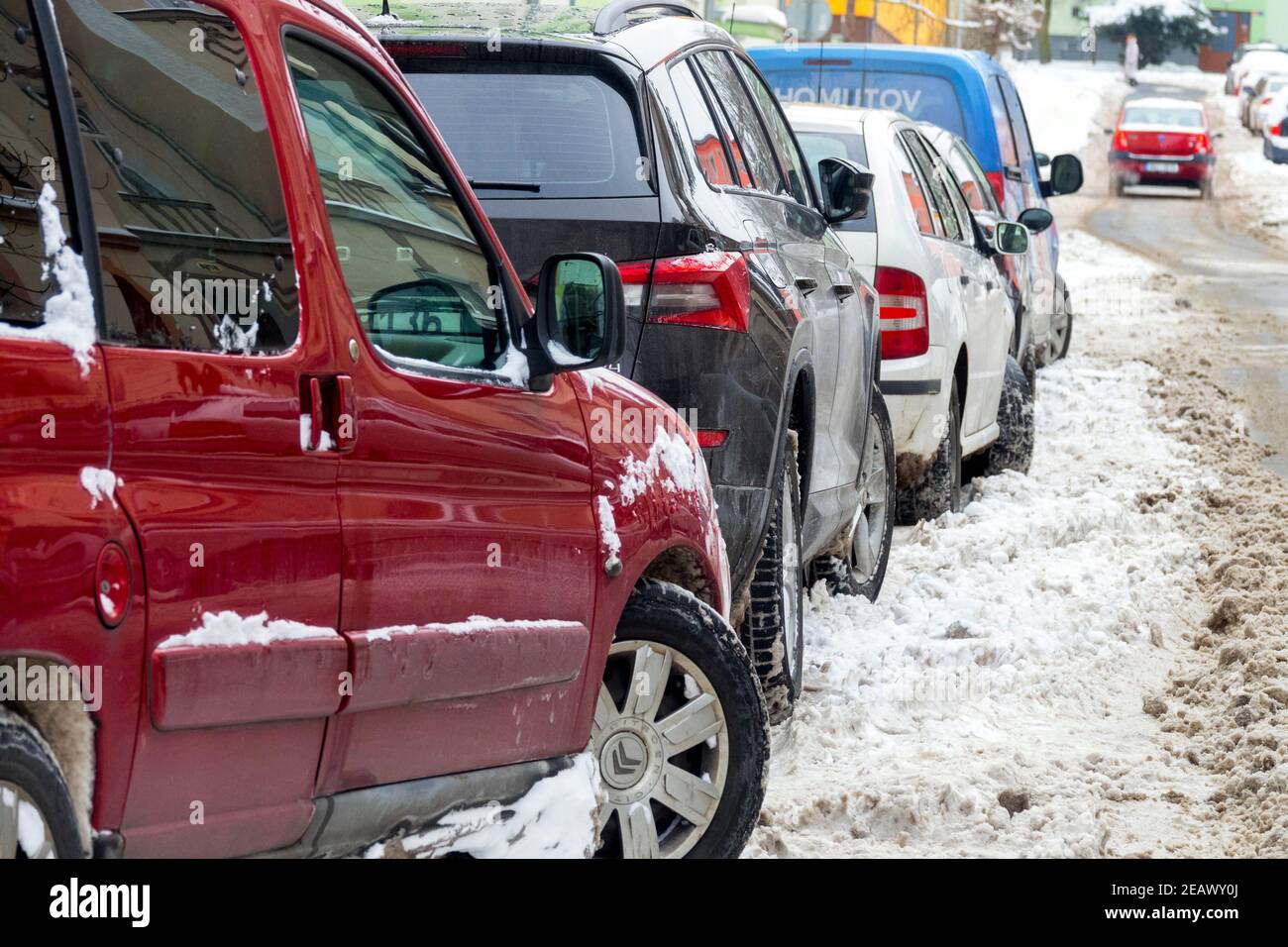 Autos parkten in einer salzigen Schneestraße im Winter Stockfoto