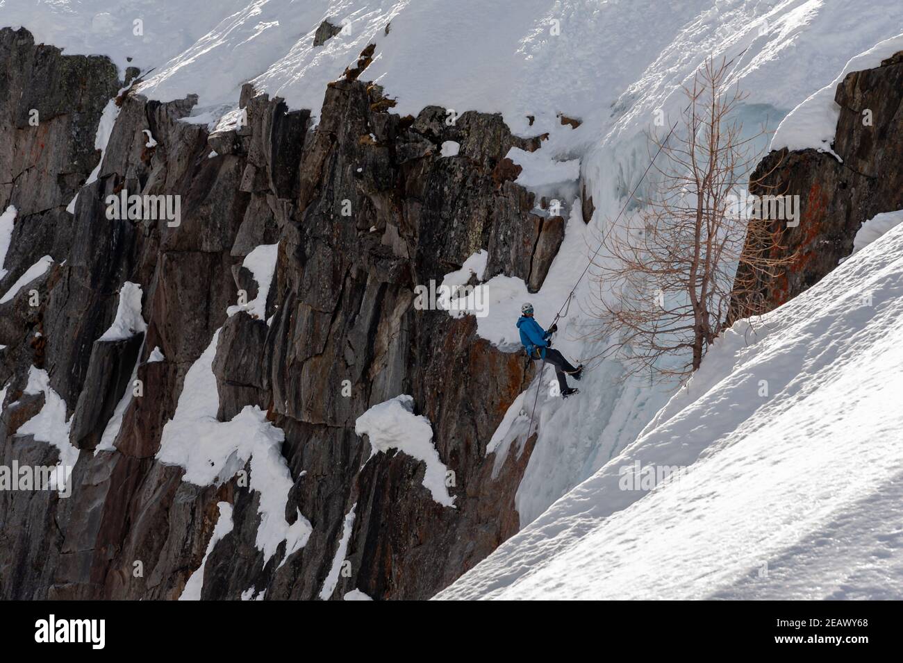 Argentiere, Frankreich - 13. März 2017: Ein Bergsteiger, der sich am sonnigen Wintertag auf den Grund des Eisfalls abseilt, um am Ende des Argentiere gla mit dem Eisklettern zu beginnen Stockfoto