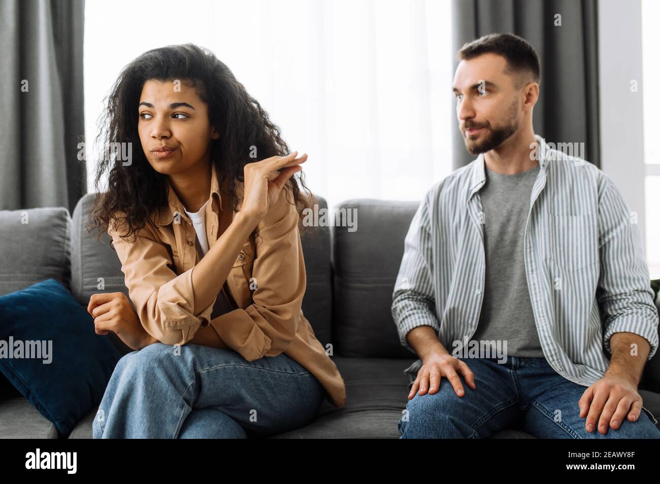 Ein Ehepaar findet die Beziehung heraus, ein Streit zwischen Liebenden. Multirassisches Paar in der Liebe streitsüchtig zu Hause auf der Couch über Haushalt oder Finanzierung Stockfoto