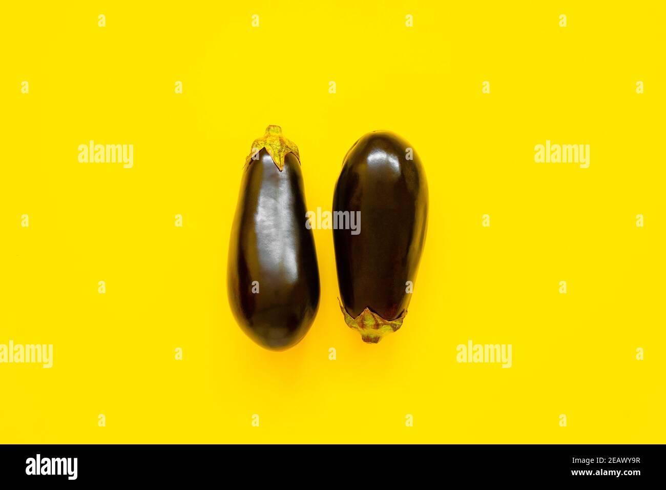 Auberginen-Paar isoliert auf gelbem Hintergrund von oben betrachtet - Flatlay-Look Stockfoto