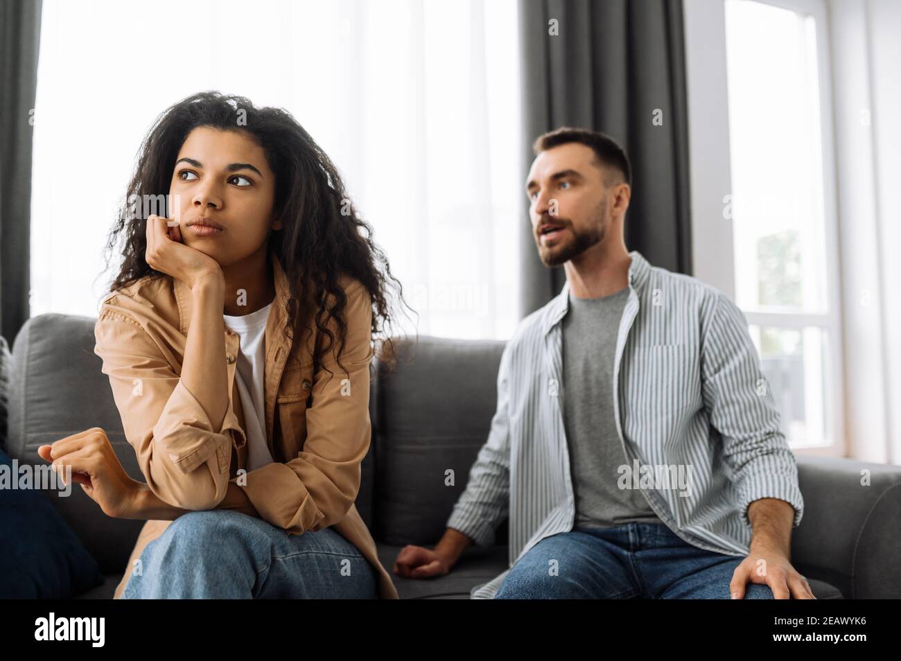 Multirassische Paar in der Liebe streiten zu Hause auf der Couch über Haushalt oder finanzielle Probleme. Die Frau wird vom Mann beleidigt und ignoriert ihn. Domesti Stockfoto