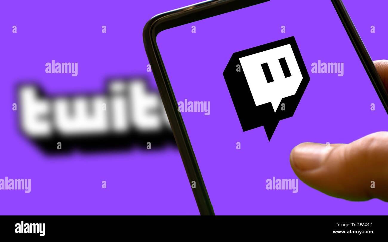 Violettes Twitch-Logo auf einem Smartphone-Bildschirm mit violettem Hintergrund und Blur-Twitch-Schriftzug. Streaming-Symbol für Spiele Stockfoto