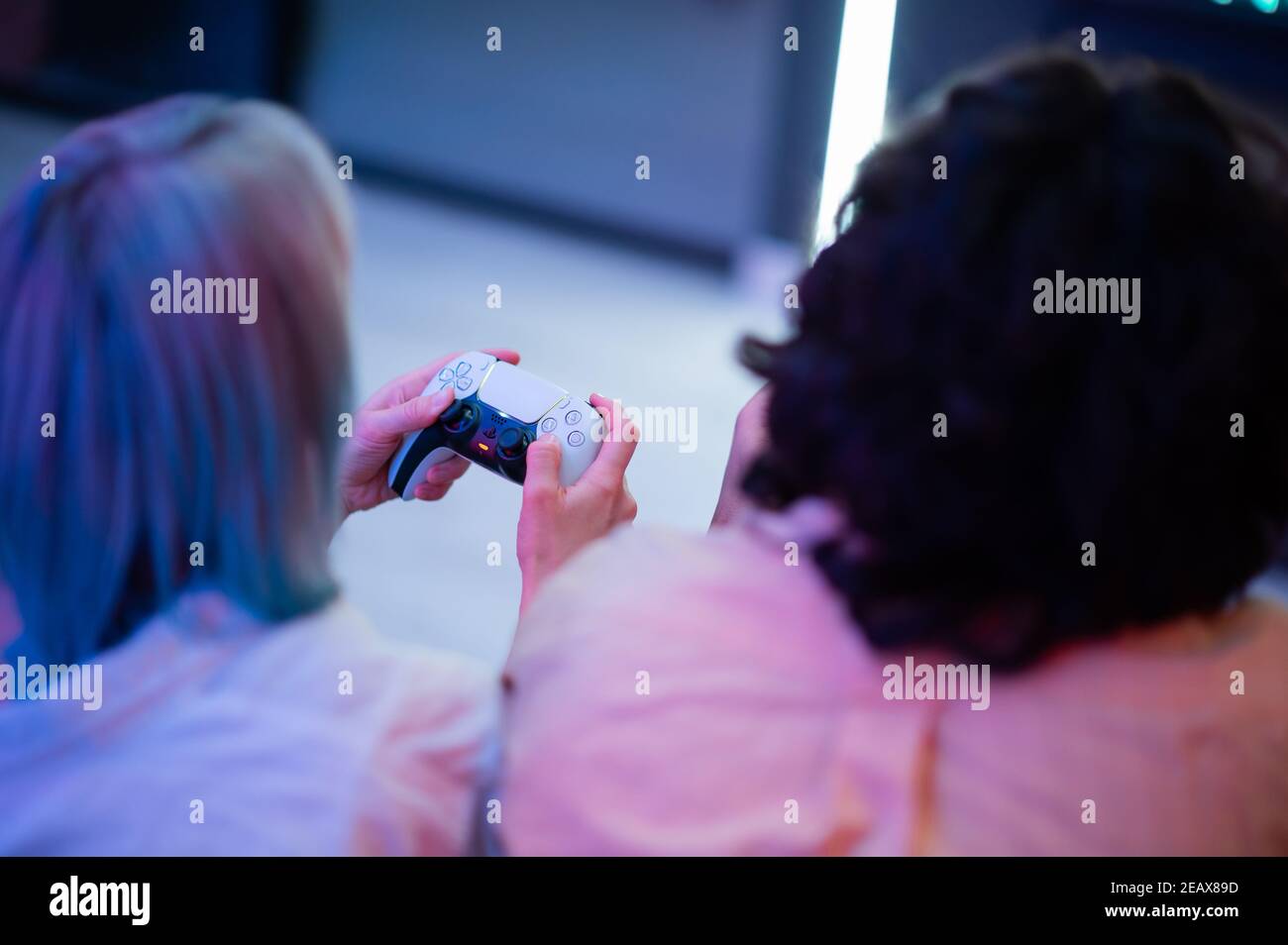 Glücklich junges Paar spielen und gewinnen ein Spiel lustige Aktivität Zuhause auf einem Sofa sitzen Stockfoto