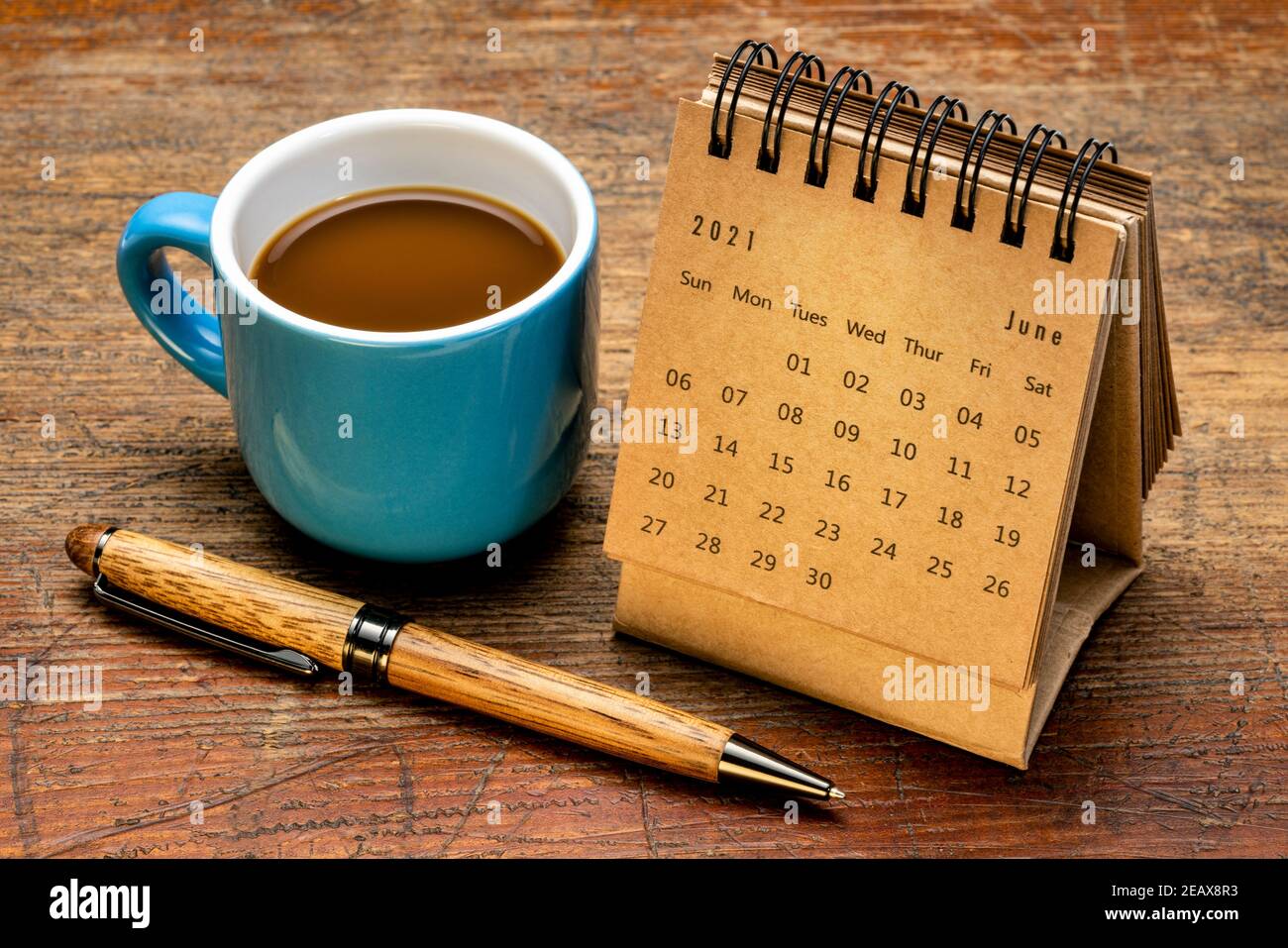Juni 2021 - Spiralkalender gegen rustikal verwittertes Holz mit einer Tasse Kaffee, Zeit und Geschäftskonzept Stockfoto