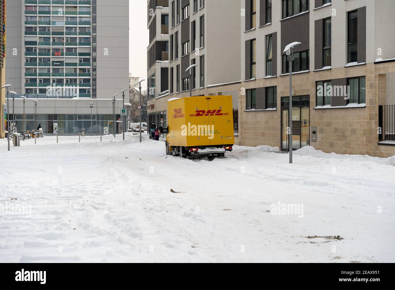 DHL-Lieferservice mit einem gelben LKW in einem Wohngebiet. Viel Schnee behindert die Arbeit. Stockfoto