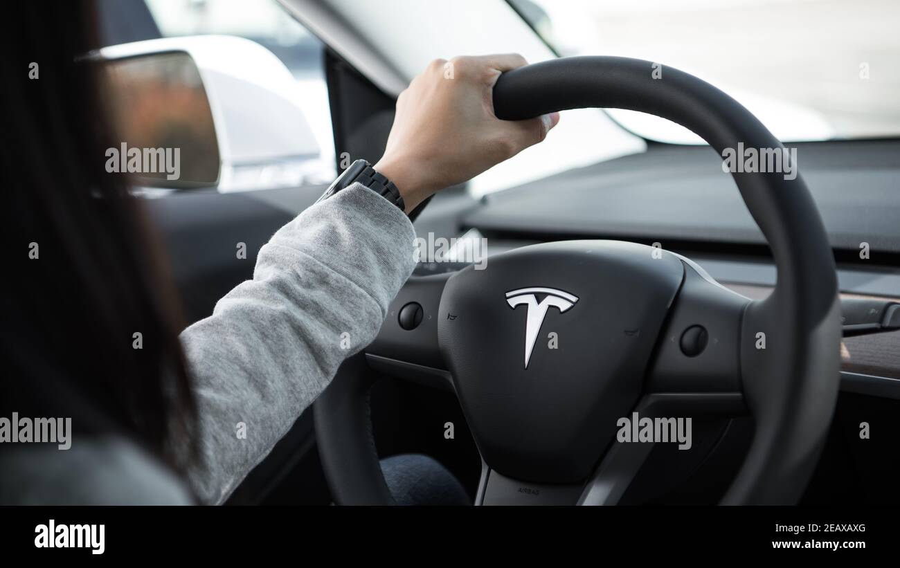 Ingenieur hält tesla Lenkrad mit einer Hand mit einem apple-Uhr am Handgelenk Stockfoto