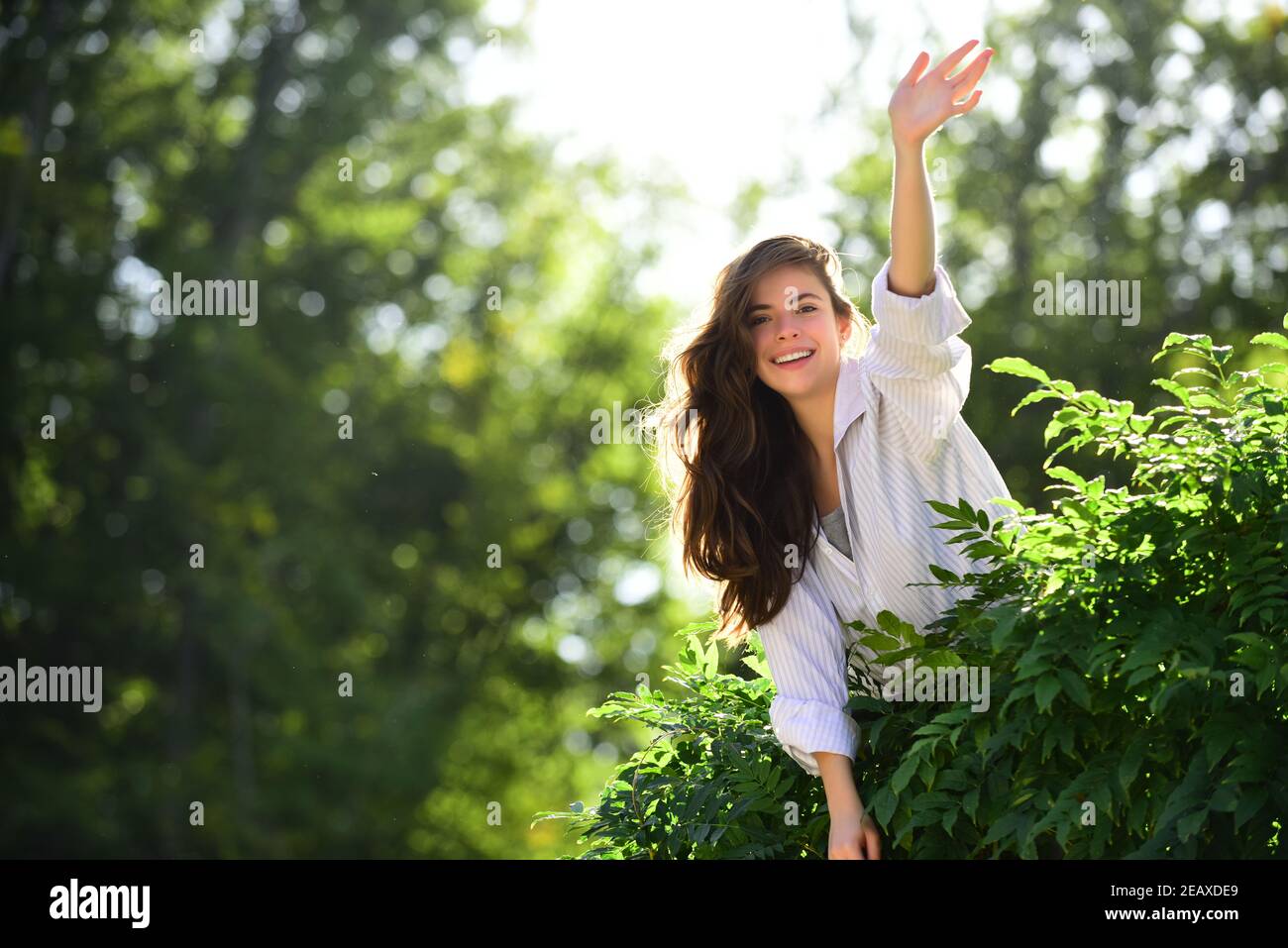 Freundliche Frau sagen Hallo Grüße auf Natur Hintergrund im Sommer oder Frühling Park. Stockfoto