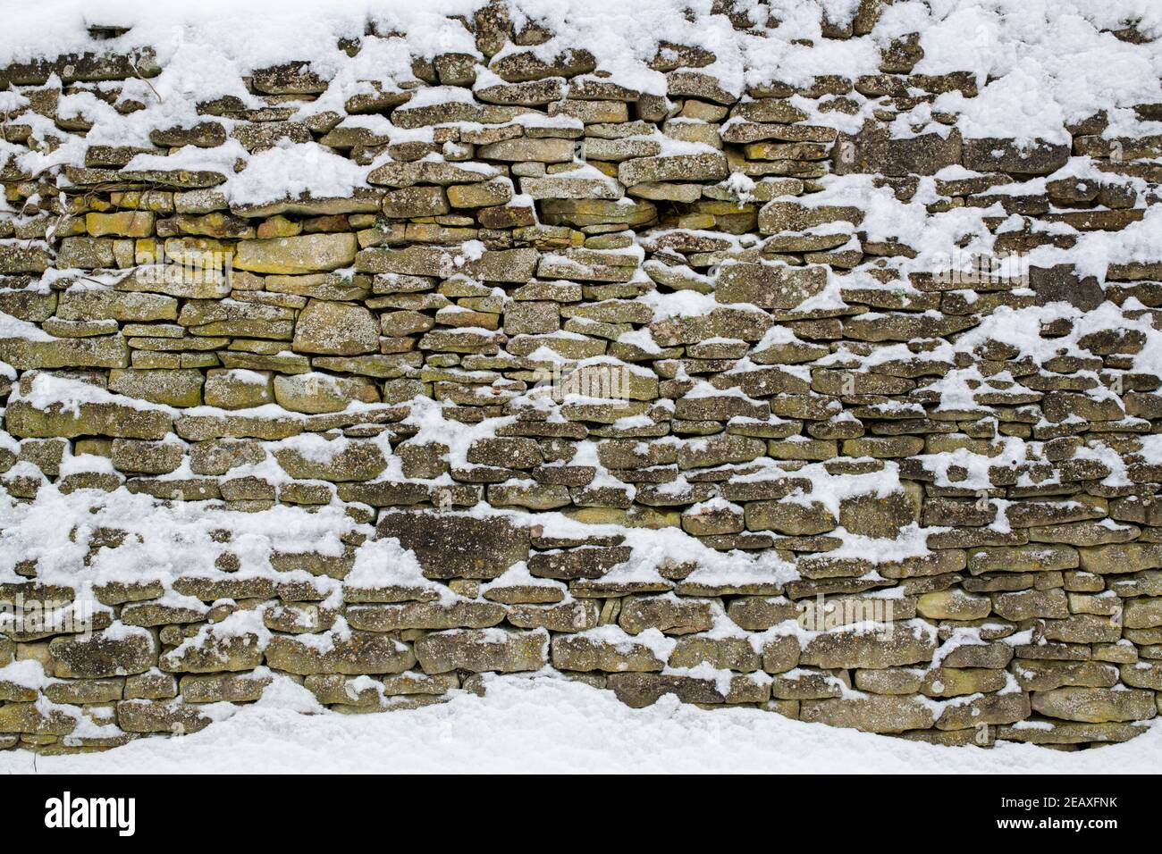 Cotswold Garten Steinmauer mit Schnee bedeckt. Swinbrook, Cotswolds, Oxfordshire, England Stockfoto