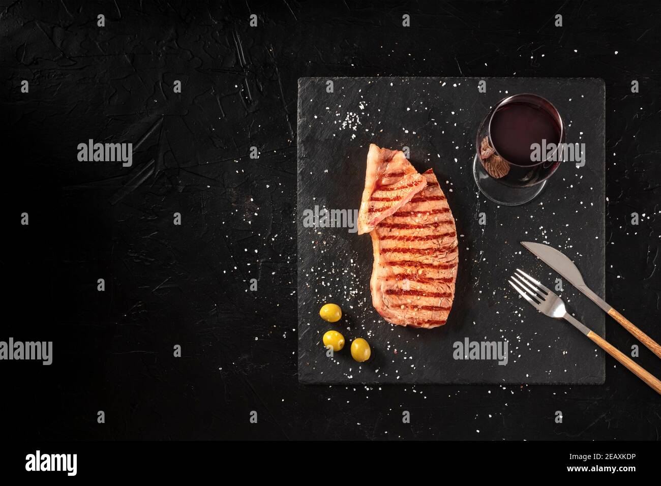Gegrilltes Rindersteak mit Rotwein, Medium, über Kopf auf dunklem Hintergrund mit Kopierfläche Stockfoto