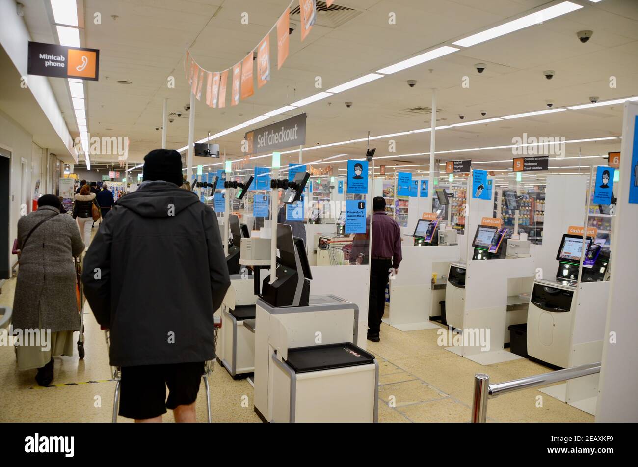Sozial entfernter Self Checkout Bereich in Sainsbury's haringey london mit Einkäufer und Mitarbeiter Stockfoto