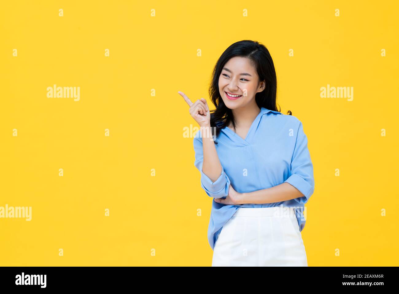Attraktive asiatische Frau bestätigt mit ihrem Finger zeigt isoliert auf Gelber Studiohintergrund mit Kopierbereich Stockfoto