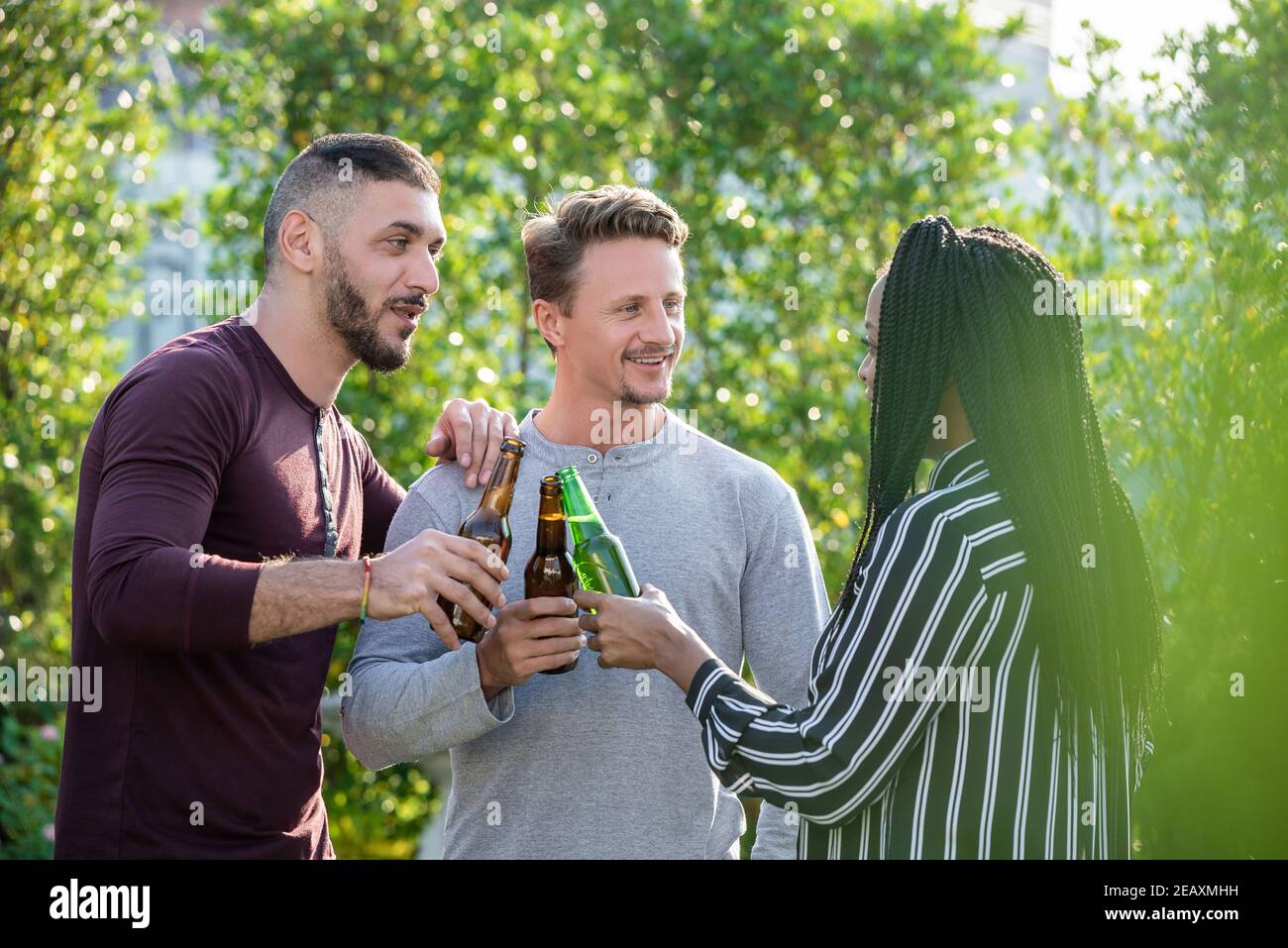 Gay Paar und afroamerikanische Frau Freund genießen Alkohol trinken Und draußen im Garten reden Stockfoto