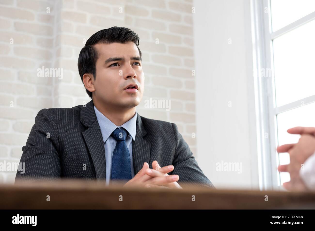 Junger hispanischer Geschäftsmann als Berater im Gespräch mit Kunden bei Der Tisch im Büro Stockfoto