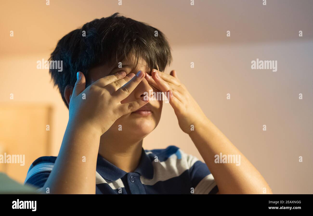 Das Kind massiert die Augen müde vom Licht Stockfoto