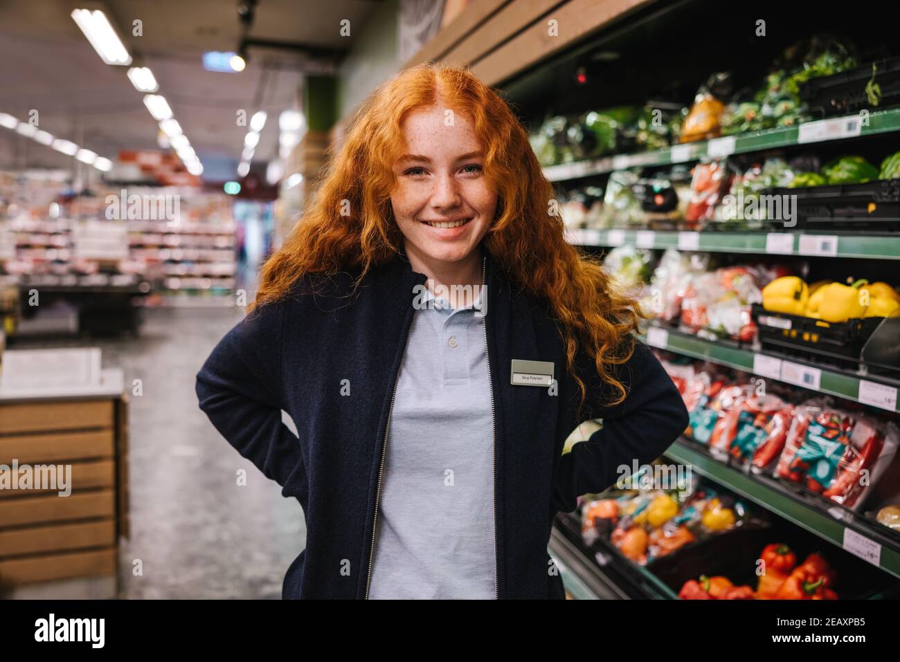 Porträt eines jungen Hypermarktangestellten. Studentin auf einem Ferienjob in einem Lebensmittelgeschäft. Stockfoto