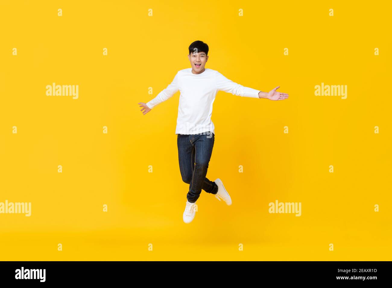 Gut aussehend und energisch asiatisch koreanisch Mann in casual Kleidung springen Mit Spannung über gelbem Studiohintergrund Stockfoto