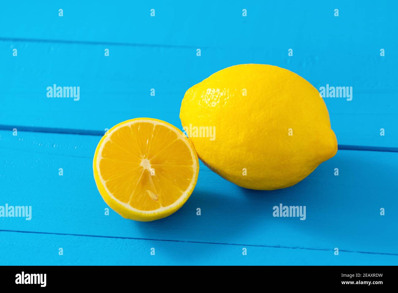 Eine ganze und eine Hälfte schneiden frische Zitrone auf blau Tabellenhintergrund Stockfoto