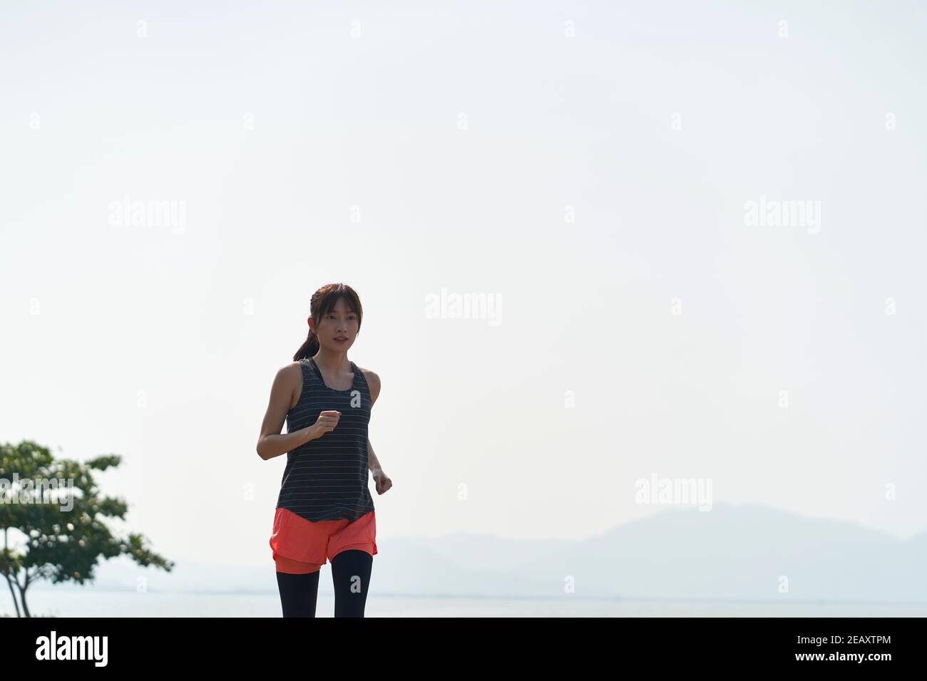 Junge asiatische Frau Jogger läuft in Seaside Park Stockfoto
