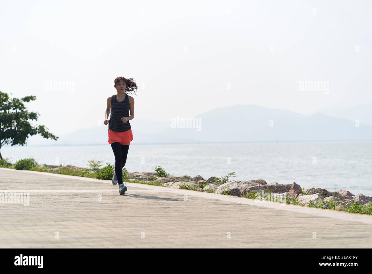 Junge asiatische Frau Jogger läuft in Seaside Park Stockfoto
