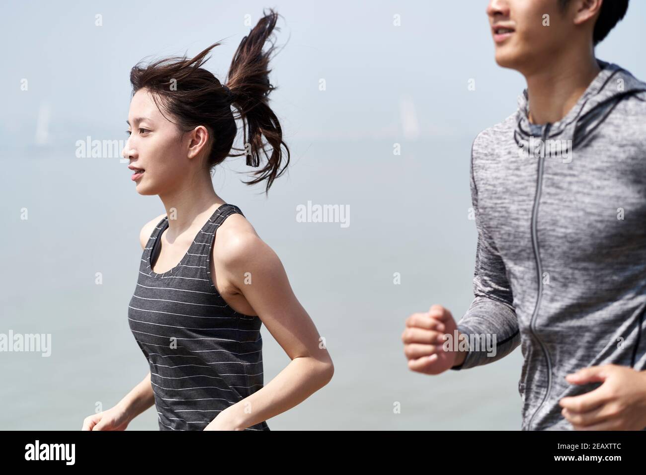 Junge asiatische Paar Mann und Frau joggen im Freien durch die Meer Stockfoto