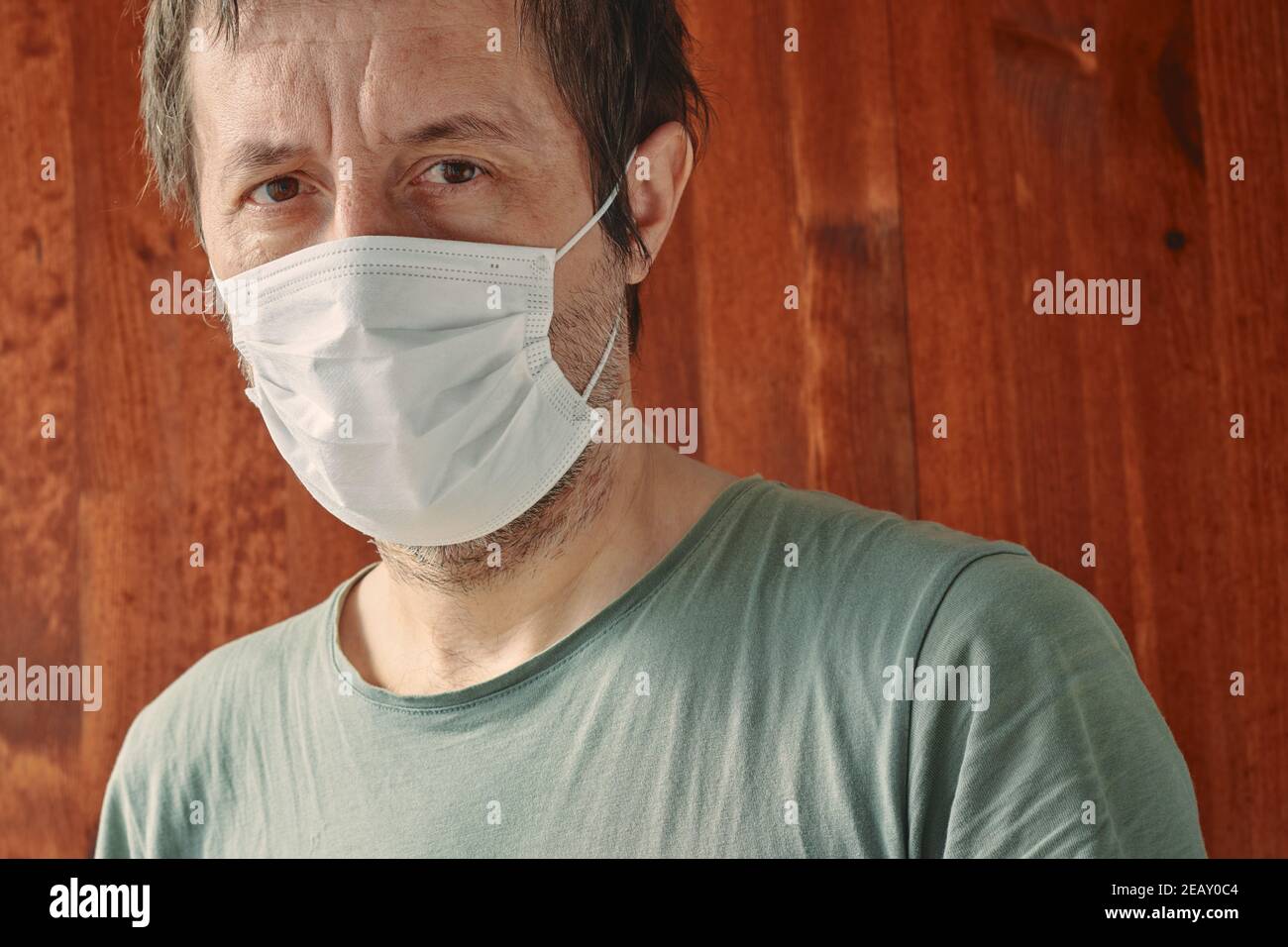Porträt des kaukasischen Mannes mit weißer chirurgischer Schutzmaske während der Pandemien von Covid-10, Blick auf die Kamera Stockfoto