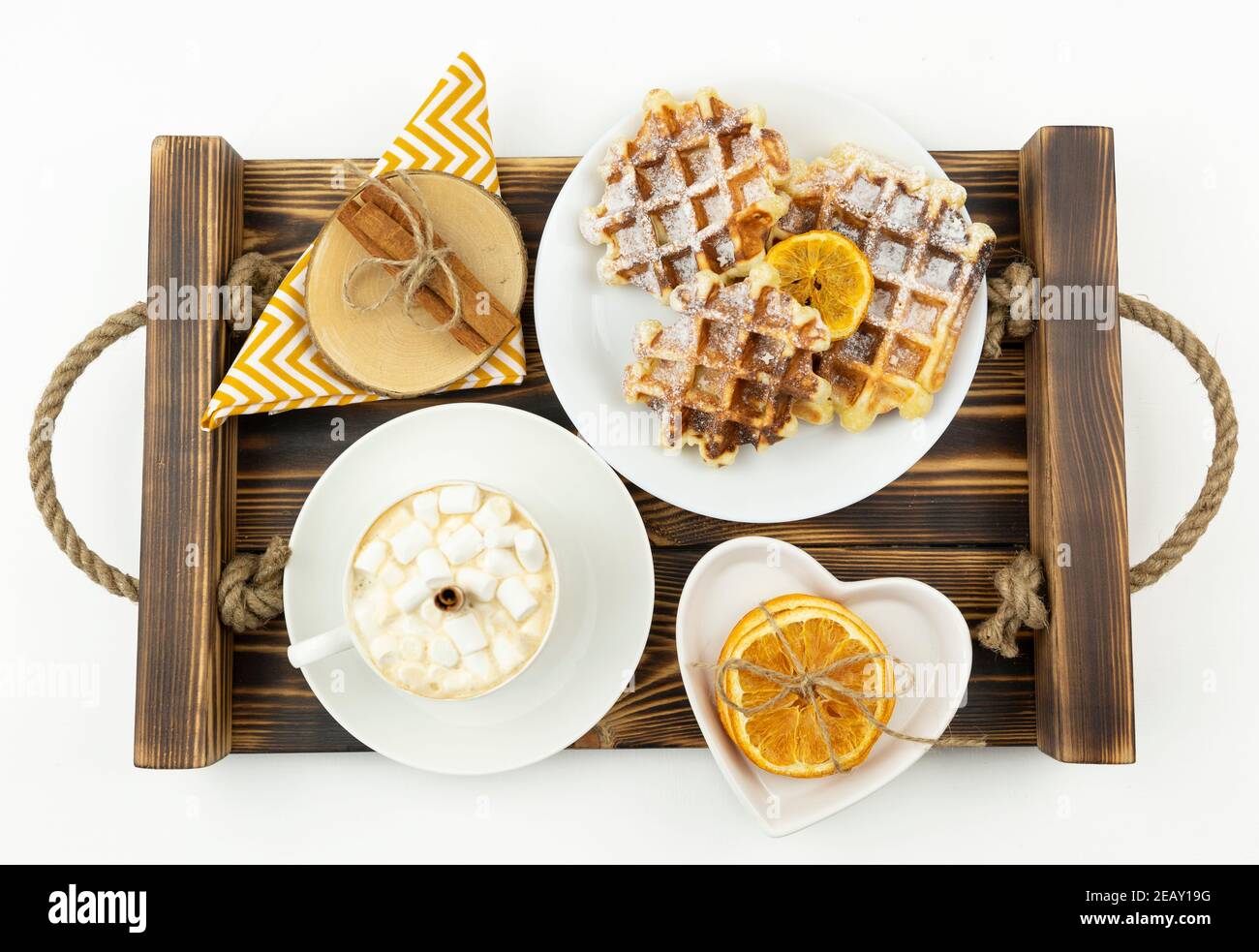 Frühes Frühstück Kaffee mit Marshmallows und einem Stock Zimt Und belgische Waffeln liegen auf einem Holztablett Stockfoto