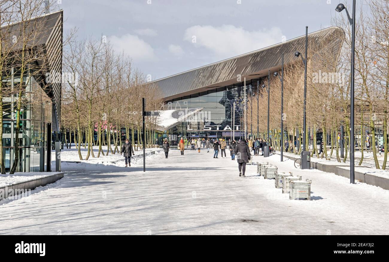 Rotterdam, Niederlande, 10. Februar 2021: Von Bäumen gesäumte und verschneite Promenade in Richtung Hauptbahnhof an einem sonnigen Wintertag Stockfoto