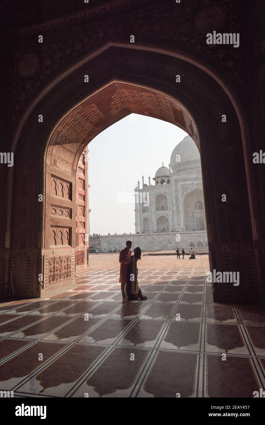 Romantisches Paar in der Nähe von Taj Mahal. Blick in schwarzer Bogensilhouette von der Moschee in Agra, Uttar Pradesh, Indien Stockfoto