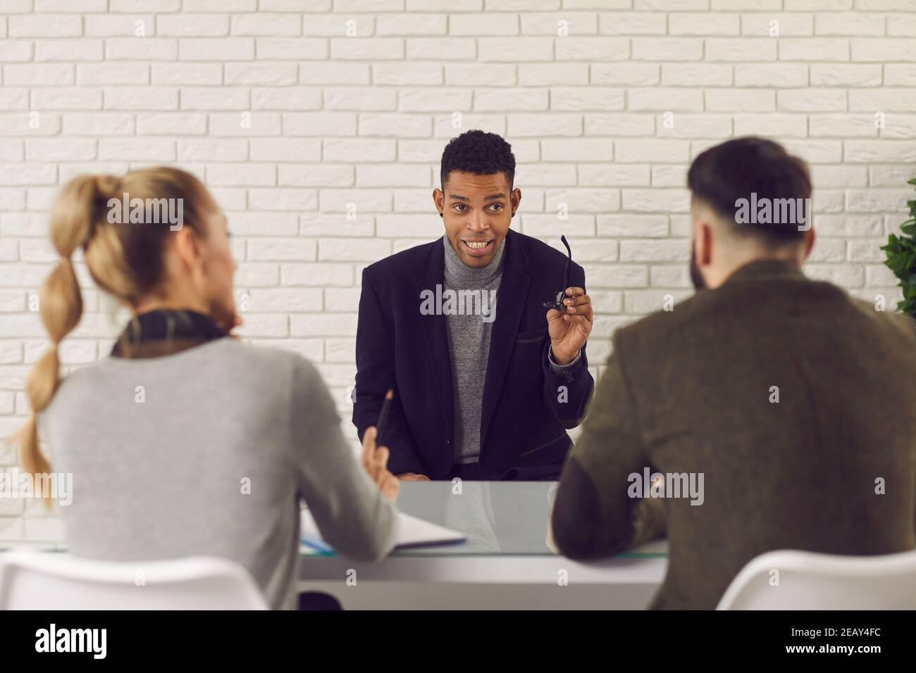 Selbstbewusster junger dunkelhäutiger Mann kommuniziert und beantwortet Fragen von Arbeitgebern beim Interview. Stockfoto