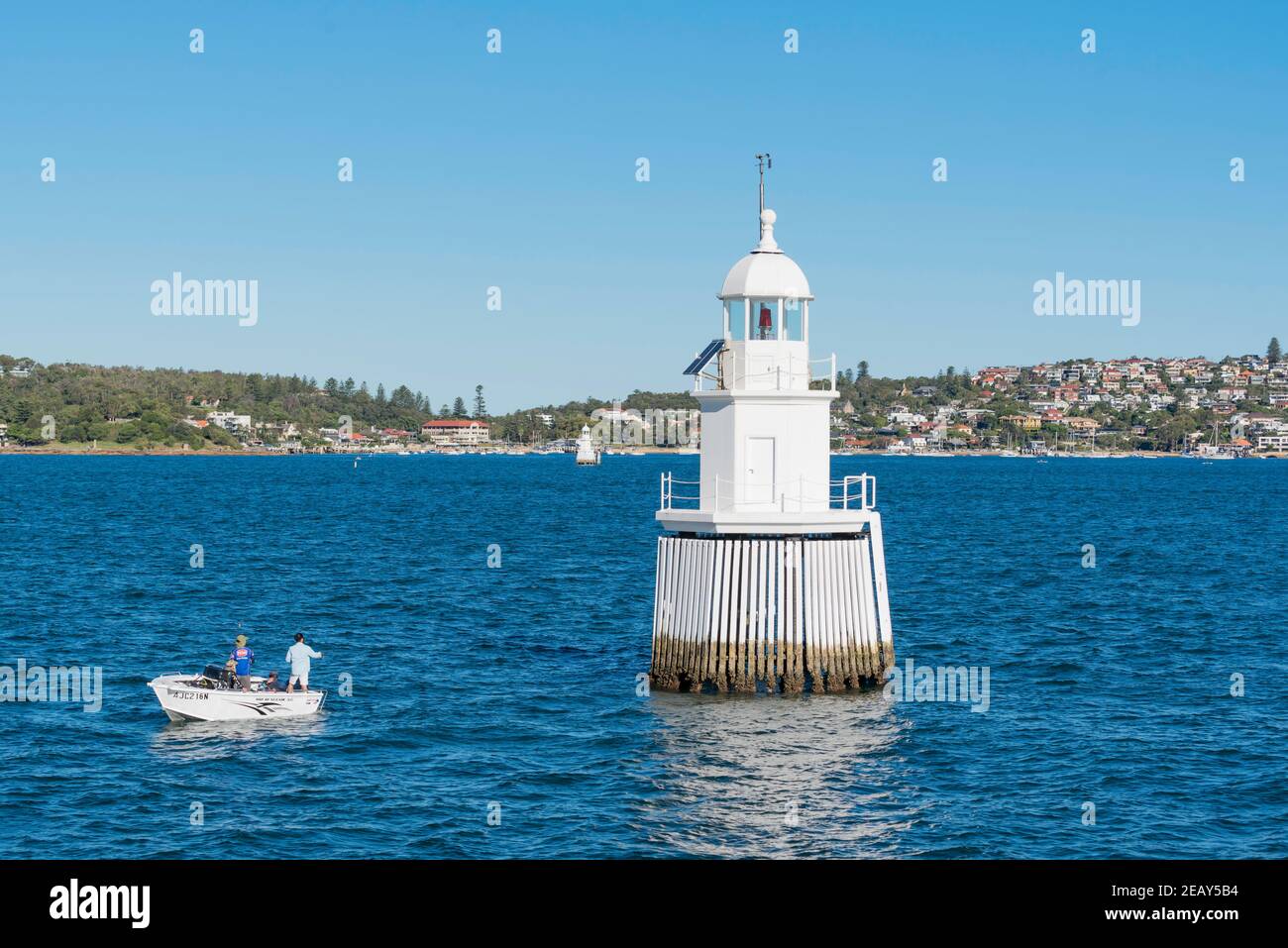 Menschen, die in einem kleinen offenen Boot in der Nähe des Western Channel Pile Leuchtturms angeln, der Sau und Pigs Reef nahe dem Eingang zum Sydney Harbour, Australien, markiert. Stockfoto