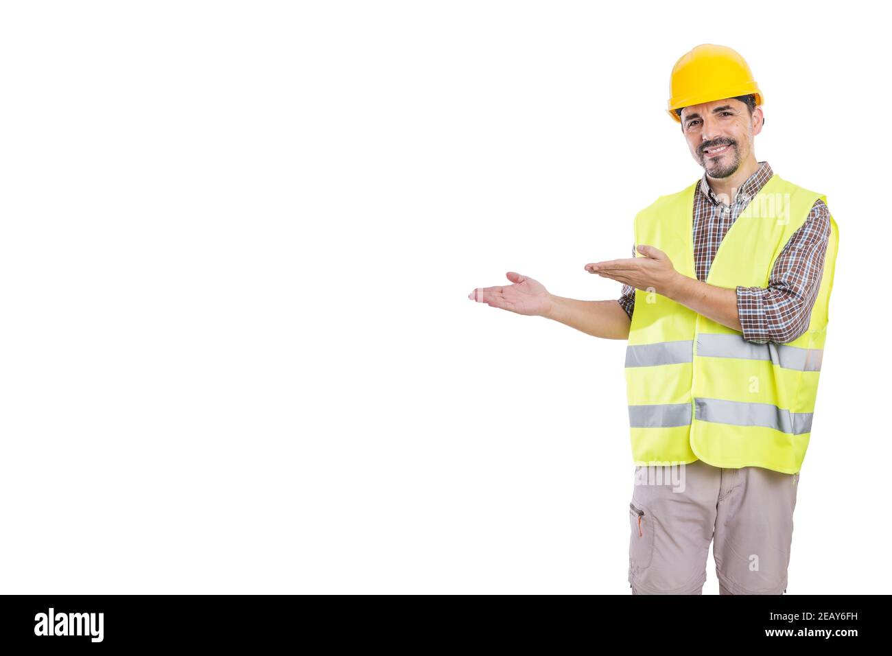 Fröhliche männliche Auftragnehmer trägt Helm und reflektierende Weste isoliert auf Weißer Hintergrund zeigt zur Seite, während man auf die Kamera schaut Stockfoto